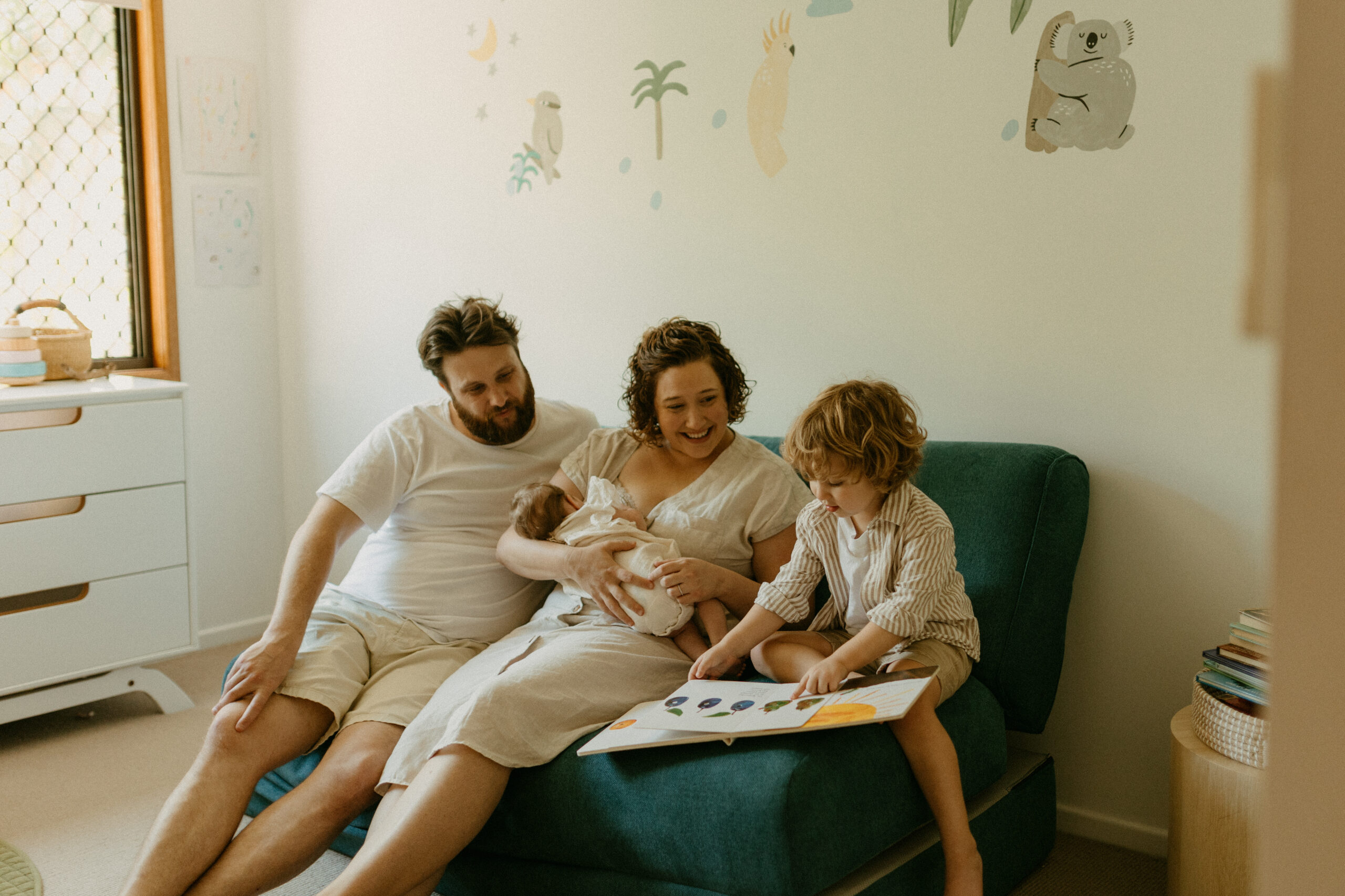 authentic family photography brisbane toddler playing with parents during newborn session, reading a book